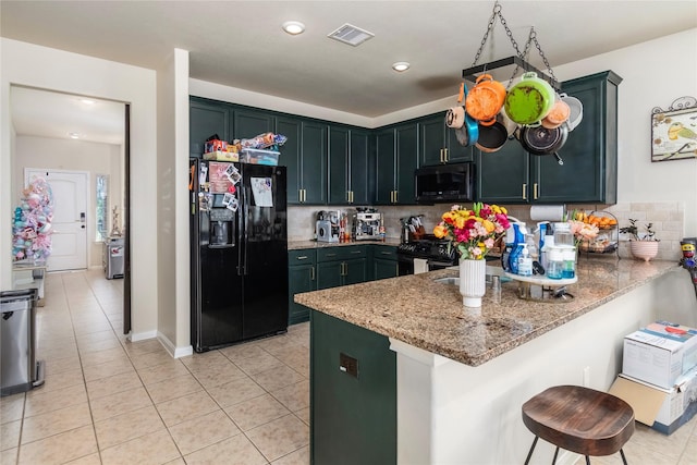 9530 Tipton Sands Dr, Humble, TX 77396 - kitchen with a peninsula, visible vents, black appliances, light stone counters, and light tile patterned flooring