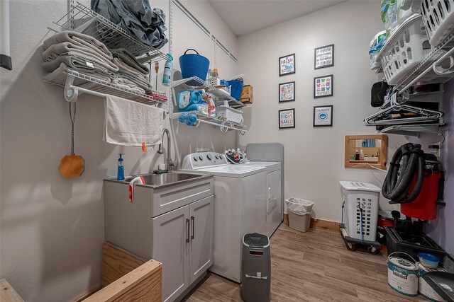 clothes washing area featuring washer and dryer, light wood finished floors, and cabinet space