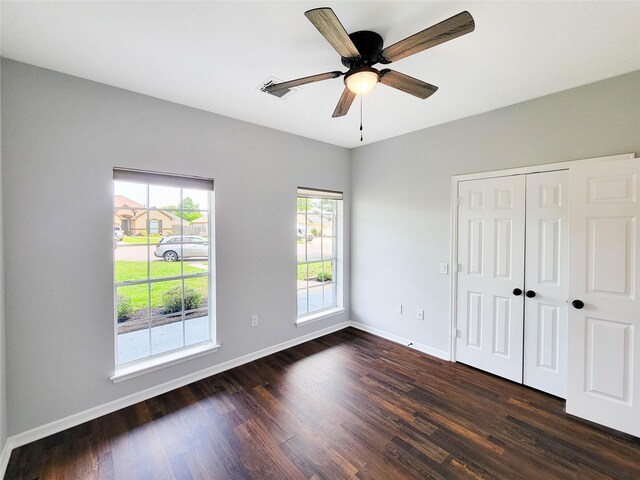 unfurnished bedroom featuring baseboards, dark wood finished floors, visible vents, and a closet