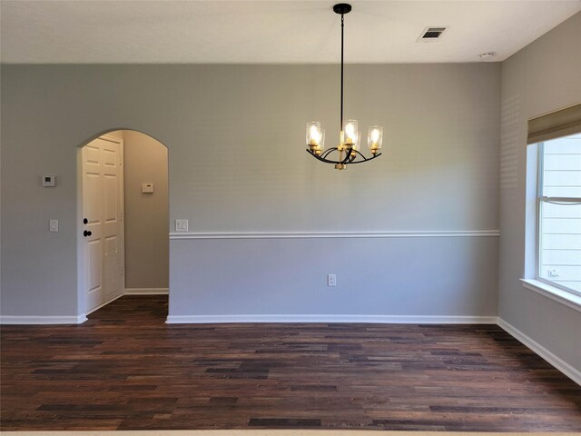 spare room with visible vents, arched walkways, dark wood finished floors, baseboards, and a chandelier