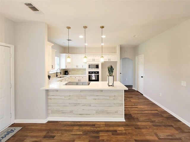 kitchen with visible vents, a peninsula, white cabinets, a sink, and black appliances