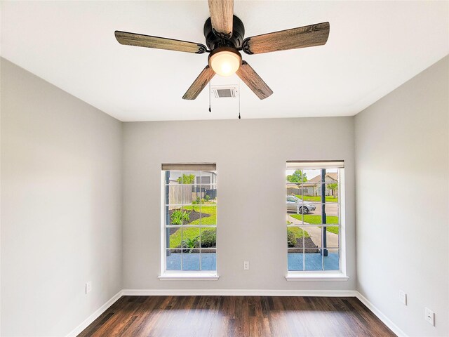 spare room with baseboards, ceiling fan, dark wood finished floors, and visible vents