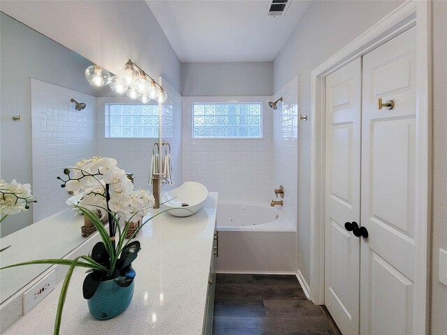 full bath featuring wood finished floors, vanity,  shower combination, and visible vents