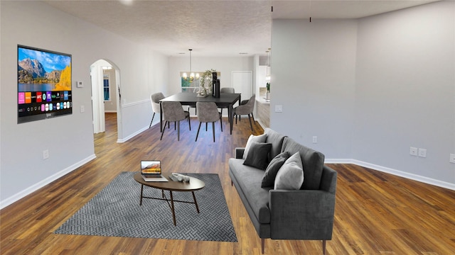9267 Inlet Cir, Montgomery, TX 77356 - living room featuring arched walkways, baseboards, wood finished floors, a chandelier, and a textured ceiling