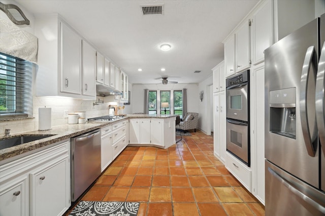 kitchen with visible vents, a peninsula, tasteful backsplash, a ceiling fan, and appliances with stainless steel finishes
