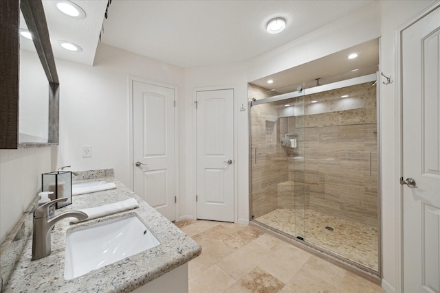 full bath with double vanity, a sink, recessed lighting, and a shower stall