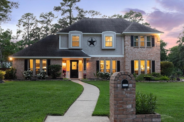 view of front facade featuring brick siding, roof with shingles, and a front lawn