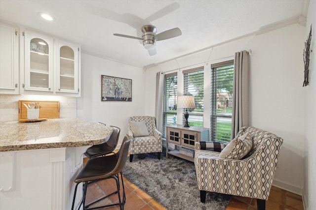 sitting room with tile patterned flooring, ornamental molding, baseboards, and ceiling fan
