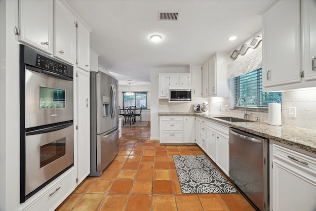 kitchen with a sink, decorative backsplash, stainless steel appliances, and visible vents