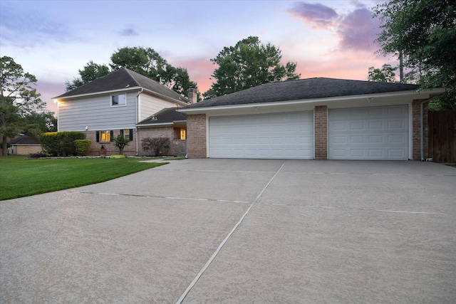 split level home featuring a lawn, brick siding, and driveway
