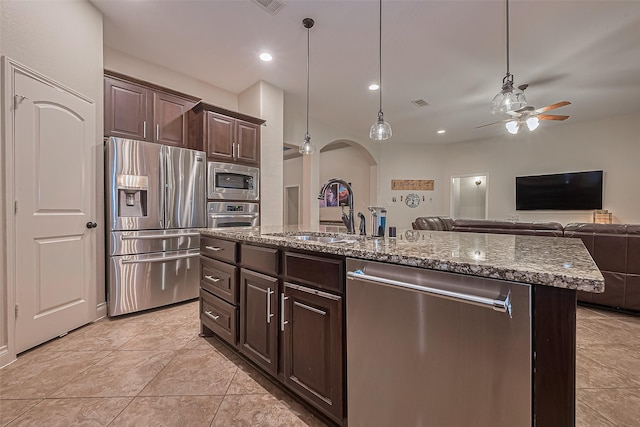 kitchen with dark brown cabinets, ceiling fan, a sink, arched walkways, and stainless steel appliances