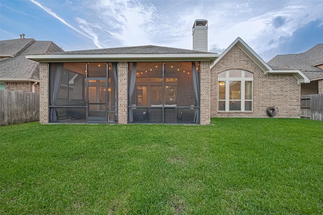 back of property featuring a sunroom, fence, and a yard