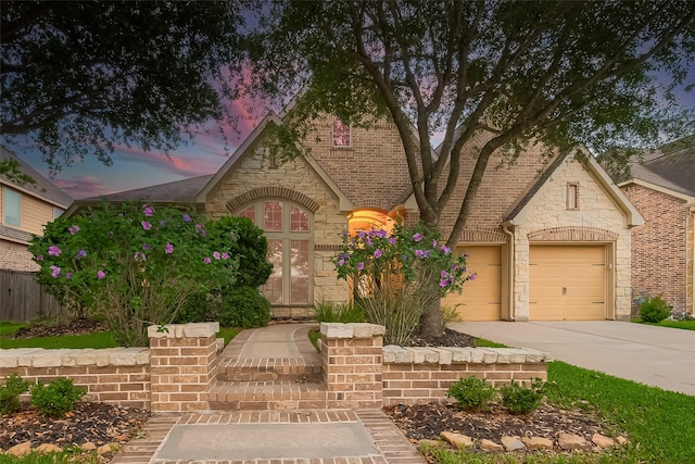 view of front facade featuring a garage, roof with shingles, driveway, and stone siding