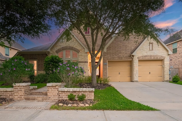 view of front of home with concrete driveway, brick siding, and stone siding