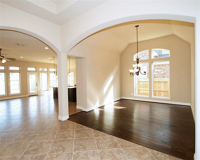 interior space featuring arched walkways, baseboards, ceiling fan with notable chandelier, lofted ceiling, and recessed lighting