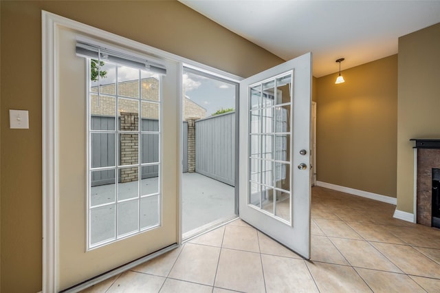 entryway with baseboards, light tile patterned floors, and a fireplace
