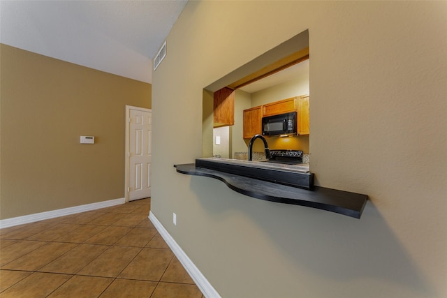 kitchen featuring dark countertops, black microwave, light tile patterned floors, and visible vents