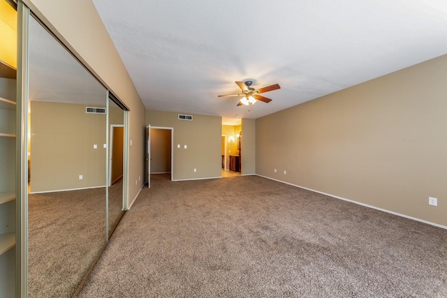 carpeted spare room with baseboards, ceiling fan, and visible vents