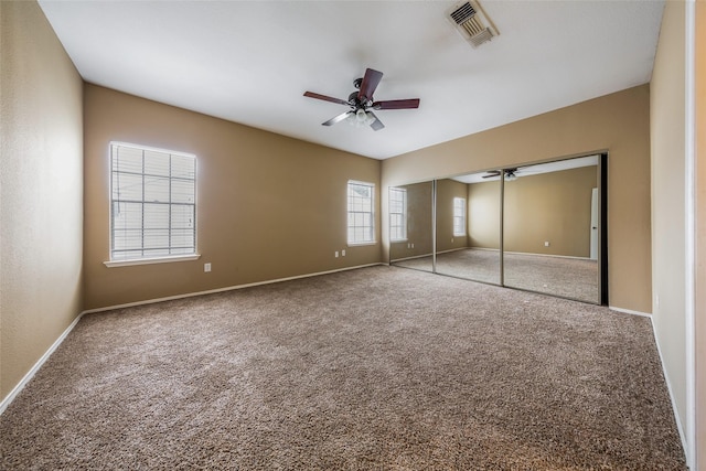 unfurnished bedroom featuring ceiling fan, carpet, baseboards, visible vents, and a closet
