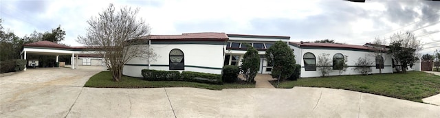 7110 W Mockingbird Ln, Pearland, TX 77584 - view of front of house featuring concrete driveway, a front lawn, an attached carport, a tiled roof, and stucco siding
