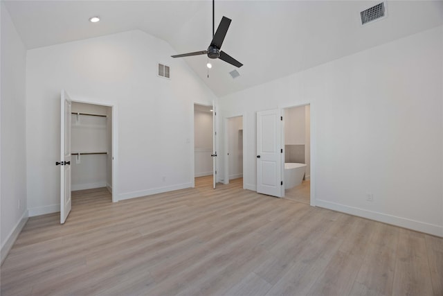 unfurnished bedroom featuring baseboards, a spacious closet, light wood finished floors, and high vaulted ceiling
