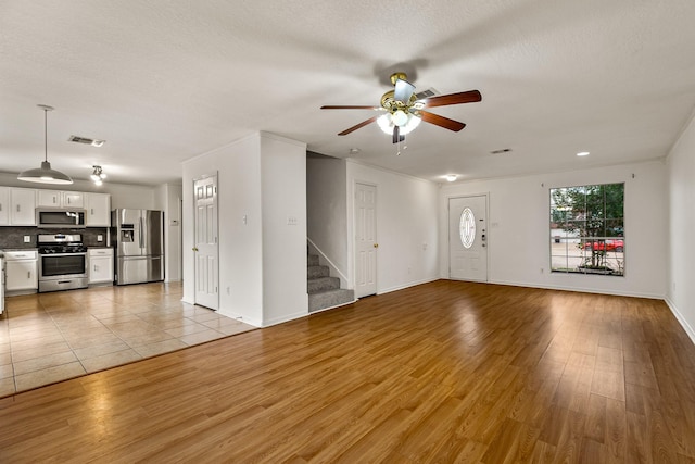 19627 Lighthouse Scene Ln, Cypress, TX 77433 - unfurnished living room featuring ceiling fan, light wood-style floors, stairs, baseboards, and visible vents