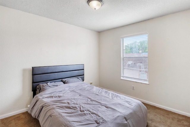 bedroom featuring baseboards, carpet, and a textured ceiling