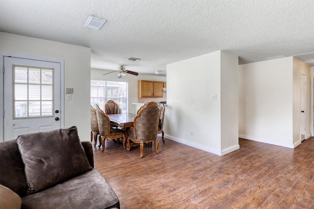 dining room featuring visible vents, wood finished floors, baseboards, a textured ceiling, and a ceiling fan