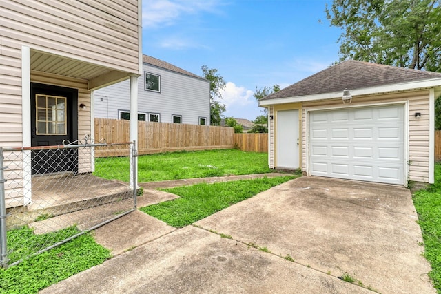 view of yard with concrete driveway, fence, an outdoor structure, and a detached garage