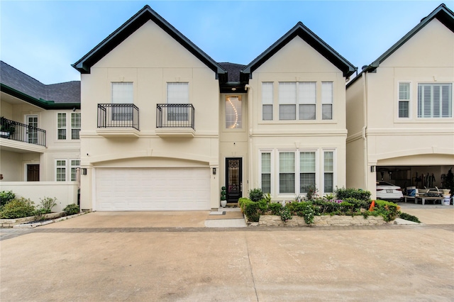 multi unit property featuring an attached garage, stucco siding, a balcony, and concrete driveway