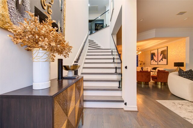 stairs featuring ornamental molding and wood finished floors