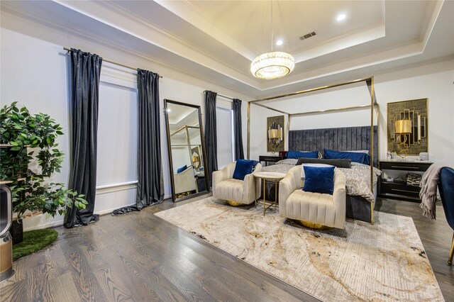bedroom featuring visible vents, a chandelier, a tray ceiling, and wood finished floors