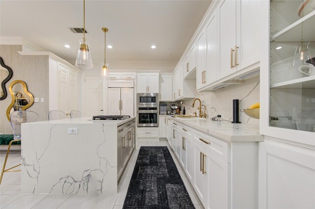 kitchen featuring visible vents, crown molding, built in appliances, a center island, and a sink