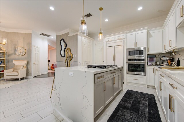 kitchen with crown molding, appliances with stainless steel finishes, a kitchen island, and visible vents