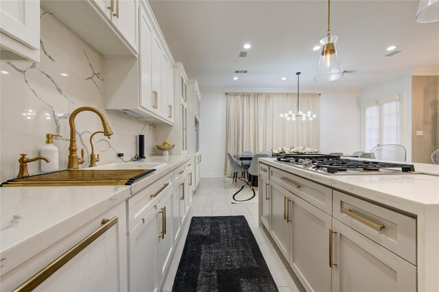 kitchen featuring stainless steel gas cooktop, recessed lighting, white cabinetry, a sink, and hanging light fixtures