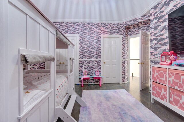 bedroom featuring crown molding, wallpapered walls, and wood finished floors