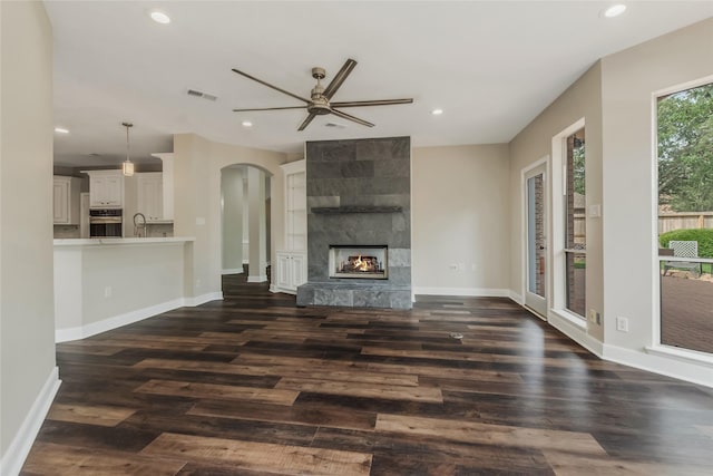 3515 Emerald Falls Ct, Houston, TX 77059 - unfurnished living room with arched walkways, ceiling fan, recessed lighting, dark wood finished floors, and a tiled fireplace