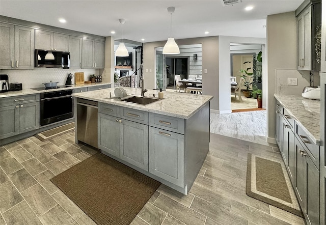 6803 Las Brisas Dr, Houston, TX 77083 - kitchen featuring light stone counters, a sink, gray cabinets, a center island with sink, and black appliances