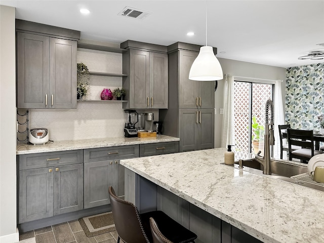 6803 Las Brisas Dr, Houston, TX 77083 - kitchen featuring open shelves, light stone countertops, visible vents, a kitchen breakfast bar, and gray cabinetry