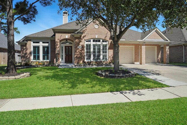 view of front of property with brick siding, a garage, a front yard, a chimney, and driveway