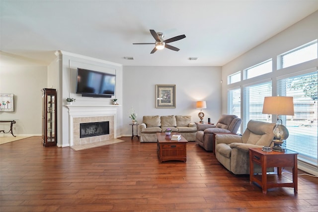 living area featuring visible vents, dark wood-type flooring, ceiling fan, and a fireplace
