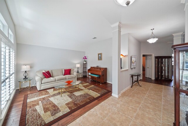 living area featuring ornate columns, light wood-style flooring, and baseboards