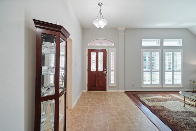 entrance foyer featuring baseboards, light tile patterned floors, and vaulted ceiling