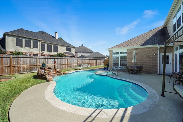 view of swimming pool with a lawn, a pool with connected hot tub, a fenced backyard, and a patio area