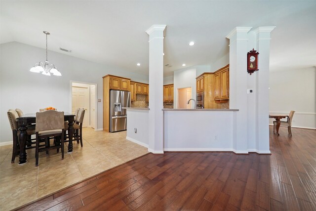 kitchen featuring a chandelier, brown cabinetry, stainless steel appliances, recessed lighting, and decorative columns