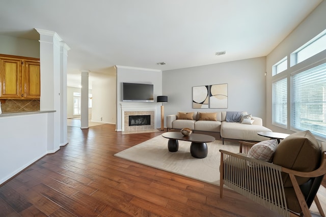 25702 Serene Spring Ln, Spring, TX 77373 - living area featuring ornate columns, a tiled fireplace, wood finished floors, and baseboards