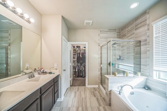 full bath with a sink, double vanity, a stall shower, and a bath