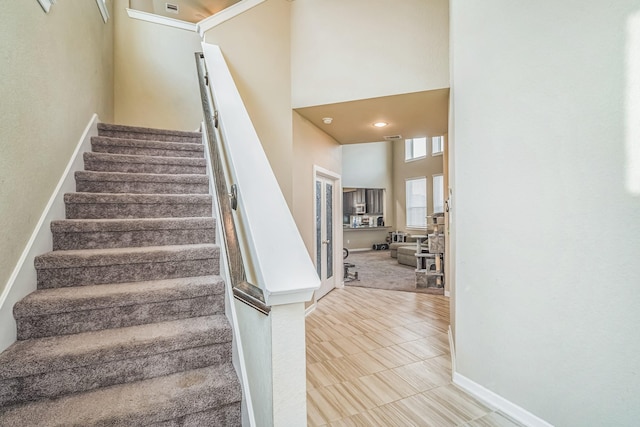 stairs with a high ceiling, baseboards, and tile patterned flooring
