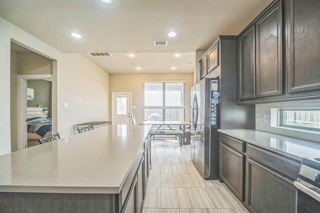 kitchen with light countertops, stainless steel appliances, visible vents, and a center island