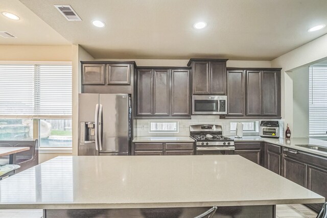 kitchen with dark brown cabinetry, visible vents, light countertops, stainless steel appliances, and recessed lighting
